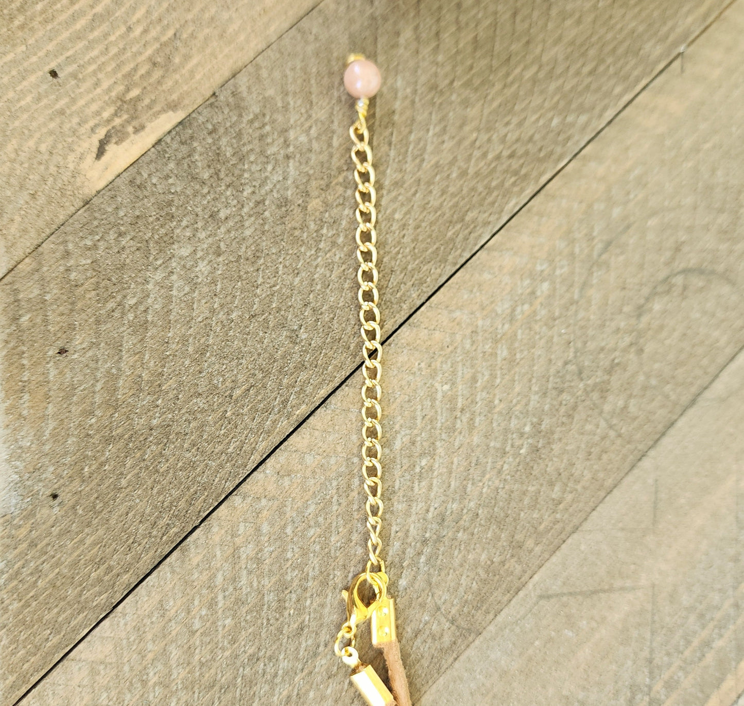 Genuine handmade shark eye moon snail pendant, accented with semi- precious sun stone beads. Tan suede 16" cord with 2" extender in gold.