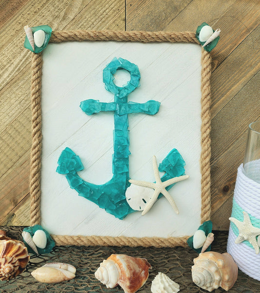 Sea glass anchor wall art in turquoise and white, surrounded with nautical jute rope, accented with a sand dollar and starfish.